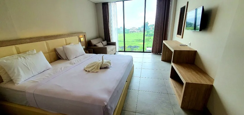Sea view room bed and sofa overlooking green fields and ocean in Bali