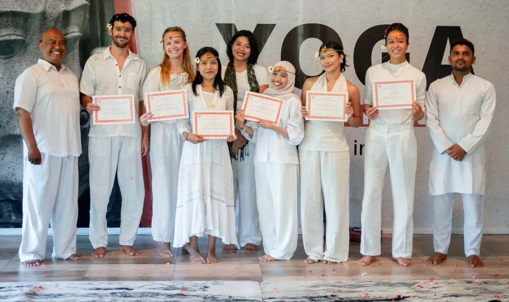 Graduates holding Yoga Alliance certificates at Bali campus ceremony