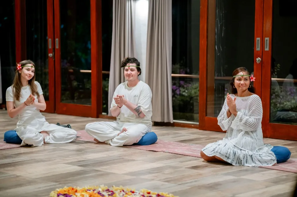 Students in prayer pose during Bali retreat ceremony