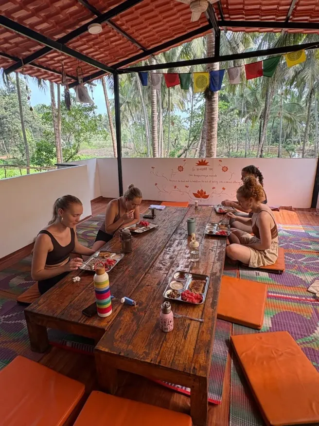Students eating vegetarian meals in the open dining space during 300 hour YTT Goa