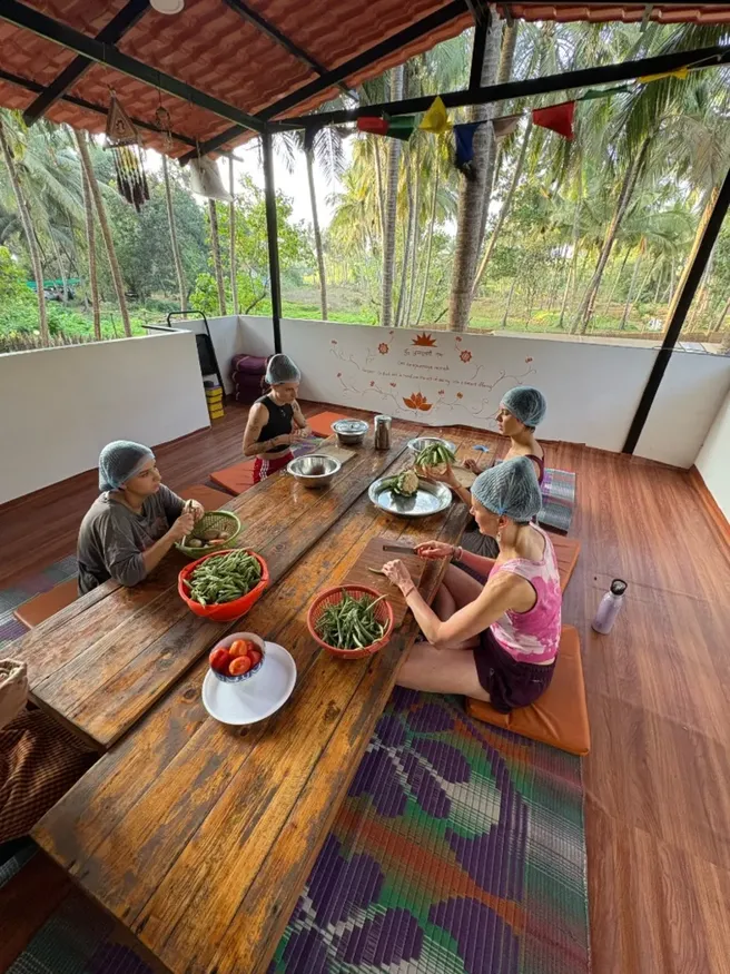 Students preparing vegetables as part of mindful community living during 300 hour YTT Goa