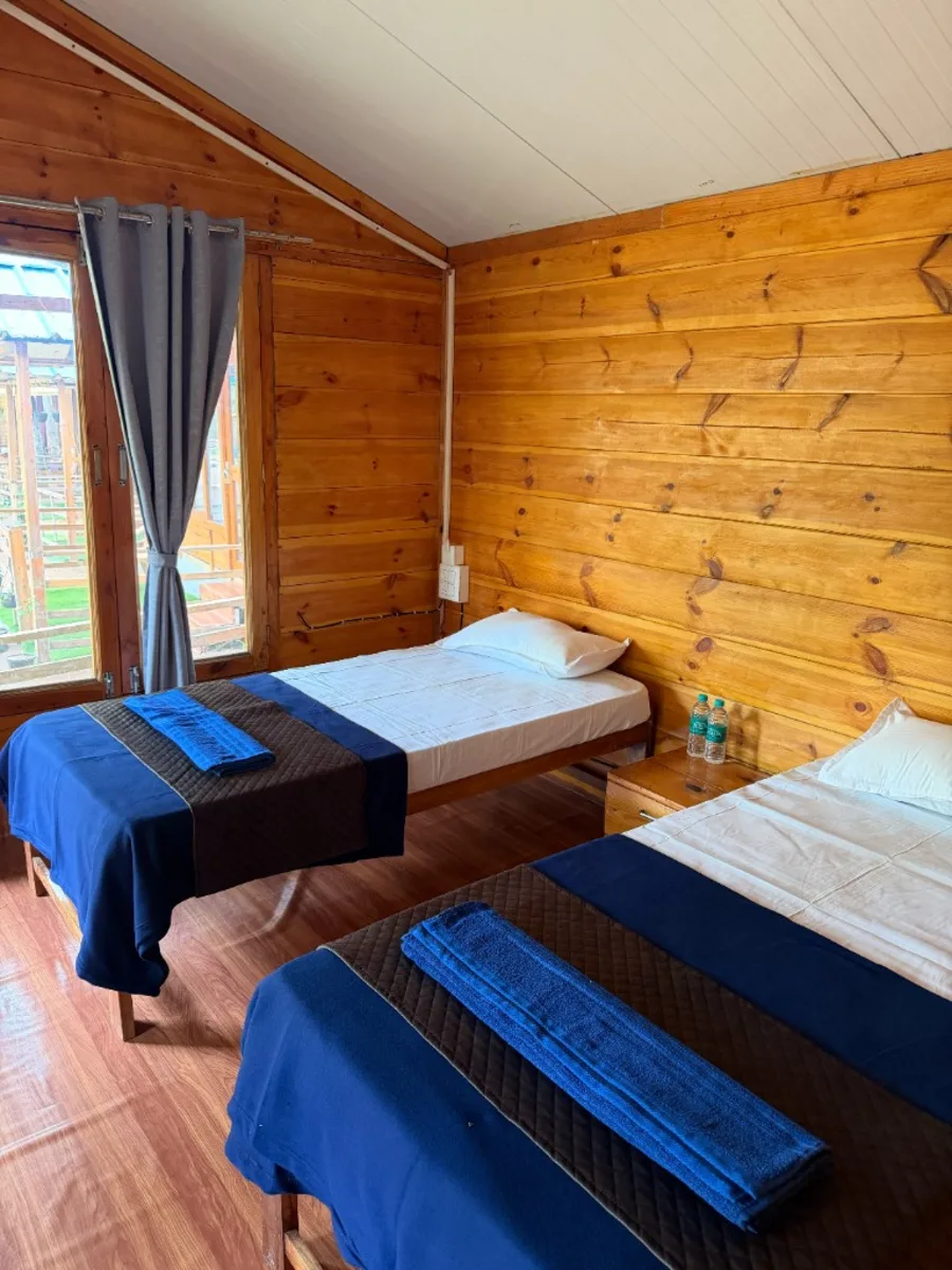 Twin beds inside wooden cottage accommodation at DivinePath Goa campus