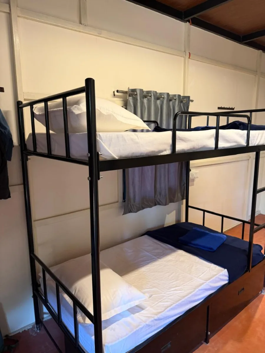 Dorm bunk with clean bedding and curtains at DivinePath 300 hour yoga teacher training Goa