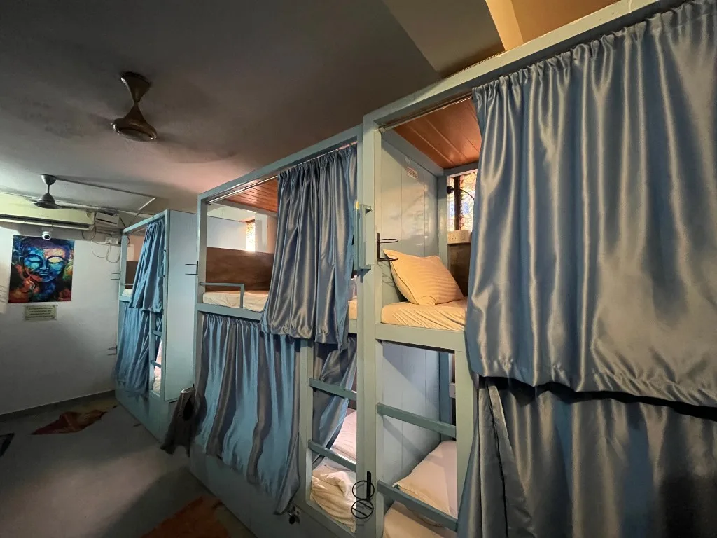 Shared dormitory with private bunk pods, curtains, and air conditioning at DivinePath yoga teacher training in Arambol, Goa