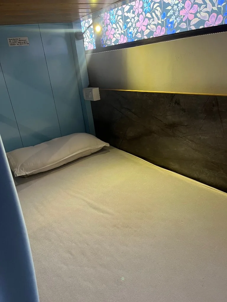Single bunk pod in Goa YTT dorm with reading light, power outlet, and privacy curtain at DivinePath