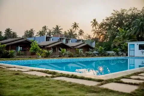 Divinepath Arambol Goa campus cottages beside the swimming pool at sunset