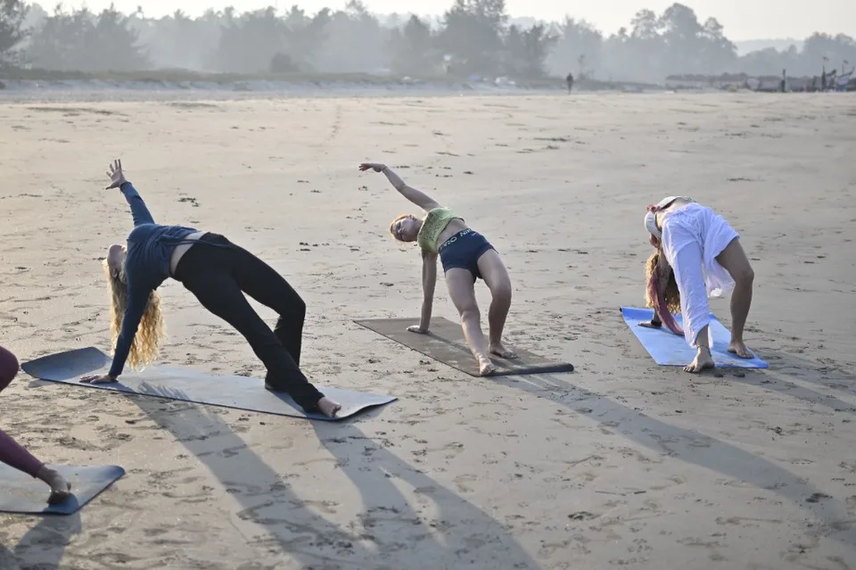 Side angle stretch on Arambol beach at sunrise