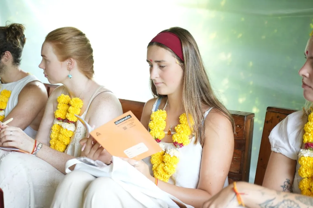 Students with marigold malas and notebooks at the start of yoga teacher training in Goa