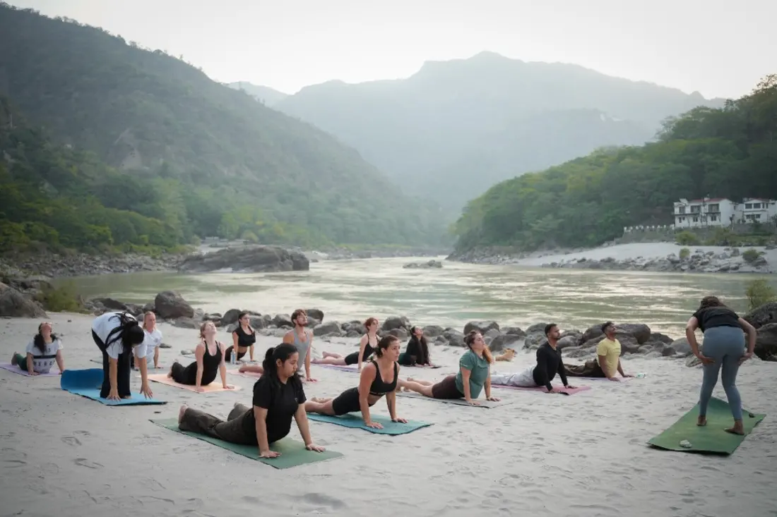 Students in a cobra pose on the riverbank in Rishikesh