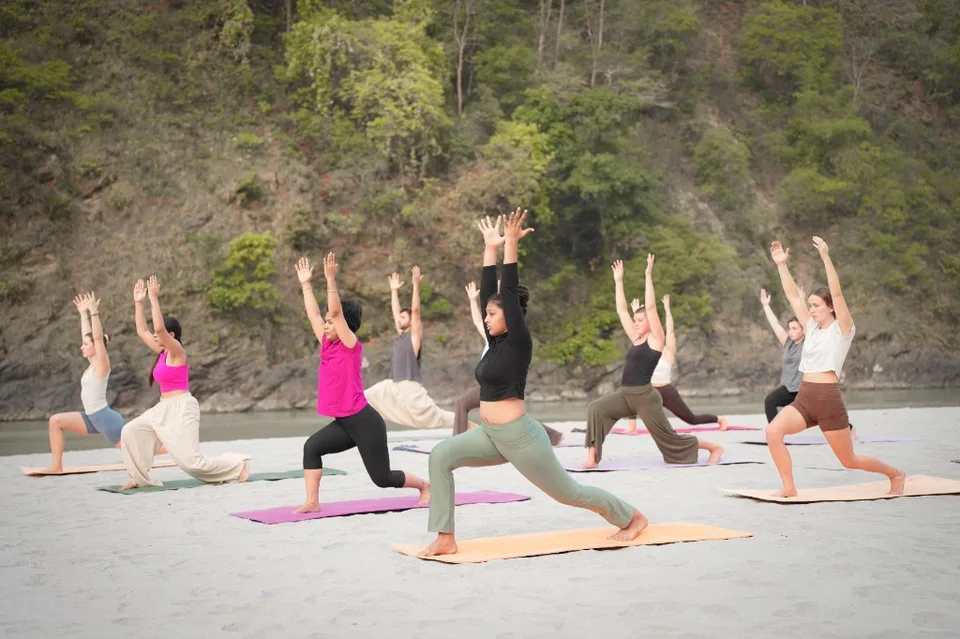 Group warrior pose by the river in Rishikesh