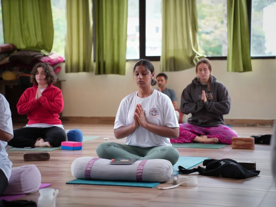 Group meditation with eyes closed in Rishikesh yoga hall