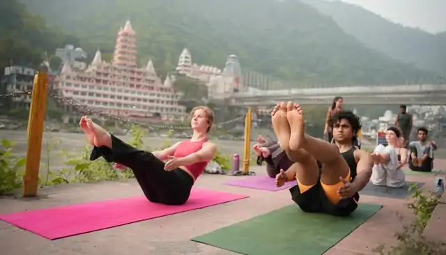 Students in navasana on the Ganga ghat — yoga teacher training in Rishikesh cost at Divinepath