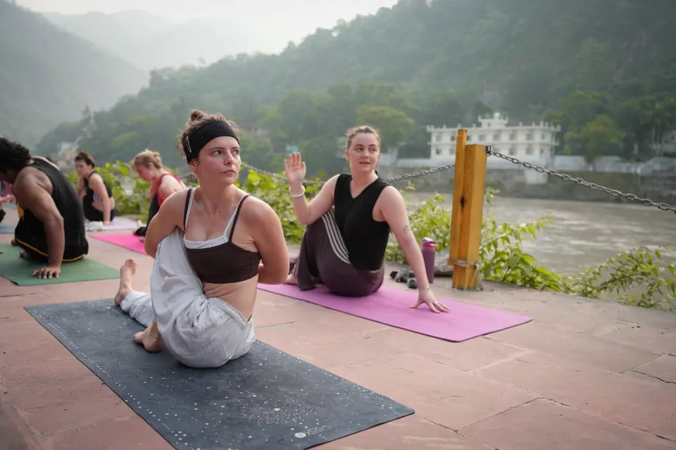 Students practising a seated twist during yoga teacher training in Rishikesh on the Ganga ghat