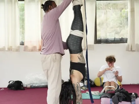 Instructor spotting a student inversion during best 200 hour yoga teacher training in Rishikesh
