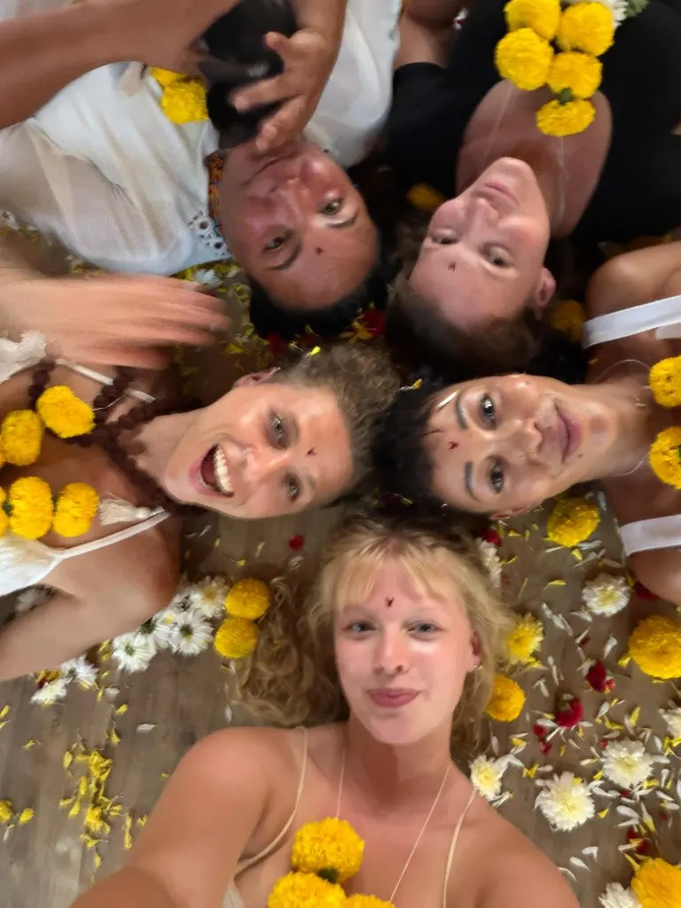 Goa yoga teacher training students celebrating together with flowers after practice