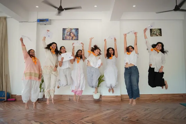 Graduates jumping with certificates after prenatal yoga teacher training in Rishikesh